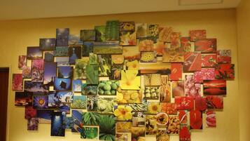 A wall covered with a variety of colorful artwork and photographs, including nature scenes, flowers, and fruits.