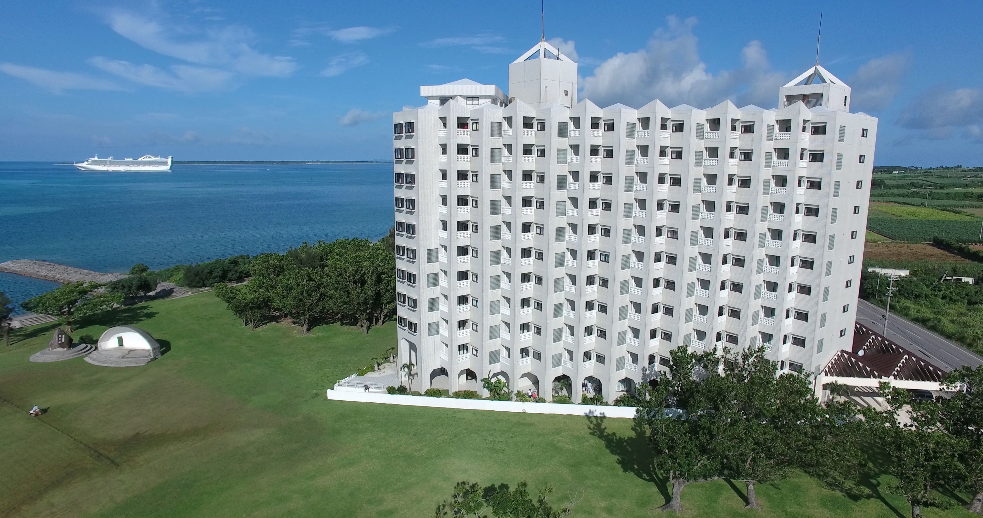 A high-rise hotel with multiple balconies, a central courtyard, and a view of the sea.