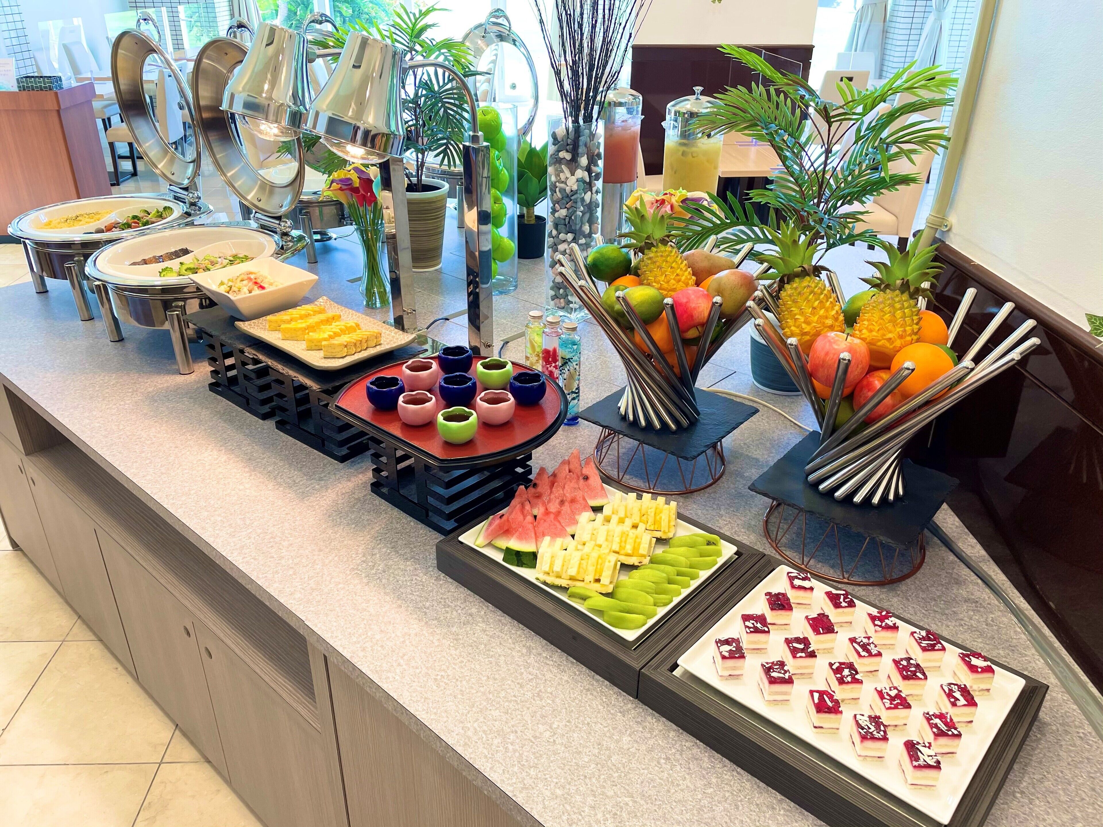 A buffet with various food items and drinks, including fruits, vegetables, and desserts.