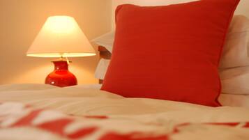 Un lit avec un oreiller rouge et une lampe rouge sur une table de chevet.