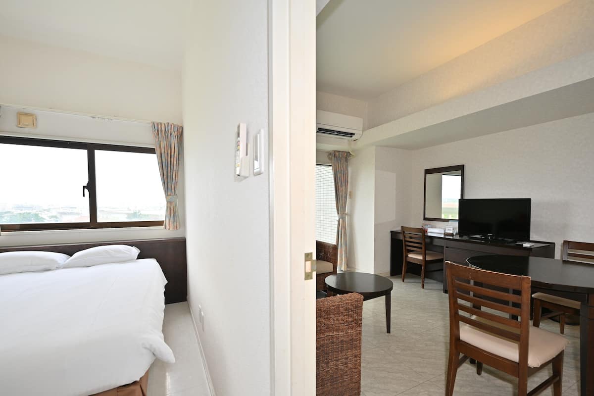 A hotel room with a bed, a desk, a chair, a television, and a window with curtains.