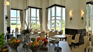 A dining area with tables, chairs, a fruit and vegetable display, and large windows with curtains. - Hotel Royal Marine Palace Ishigakijima (Ishigaki)