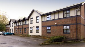 A multi-story building with a parking lot in front. - Premier Inn Stockport South (Stockport)