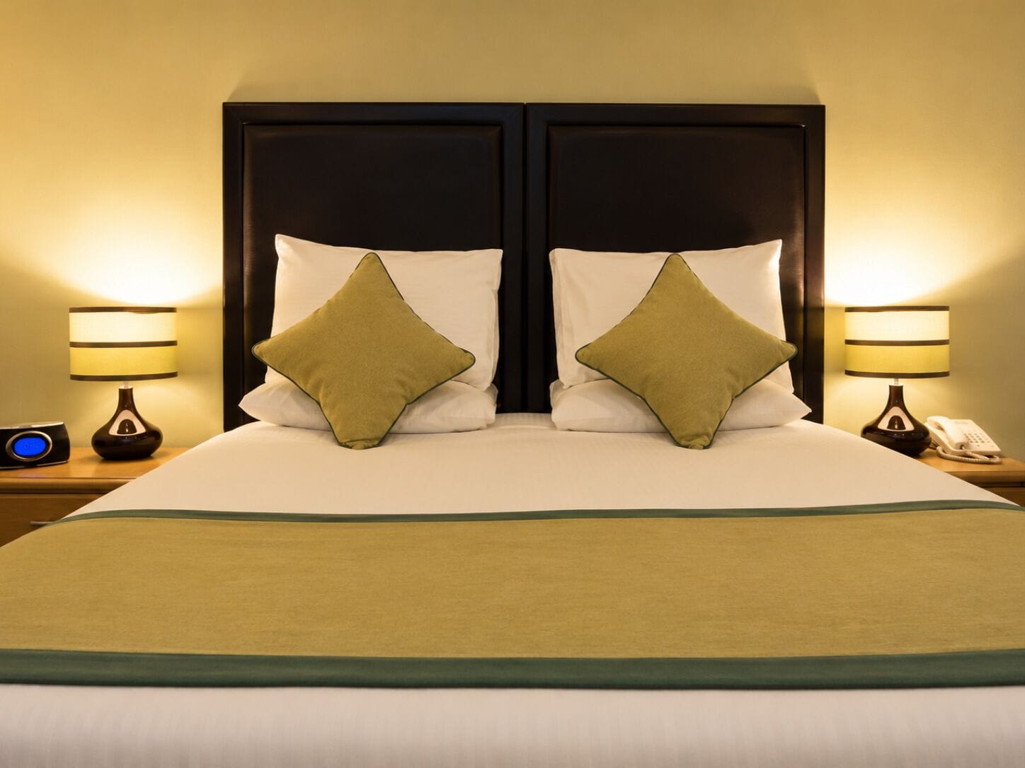 A double bed with two pillows, a bedside table with a lamp, and a phone.