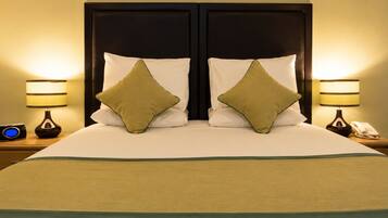 A double bed with two pillows, a bedside table with a lamp, and a phone.