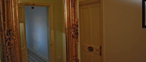 Un couloir orné d’un grand miroir et d’une porte portant un numéro.