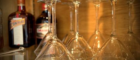Varias copas de vino sobre una barra, con botellas de licores al fondo.