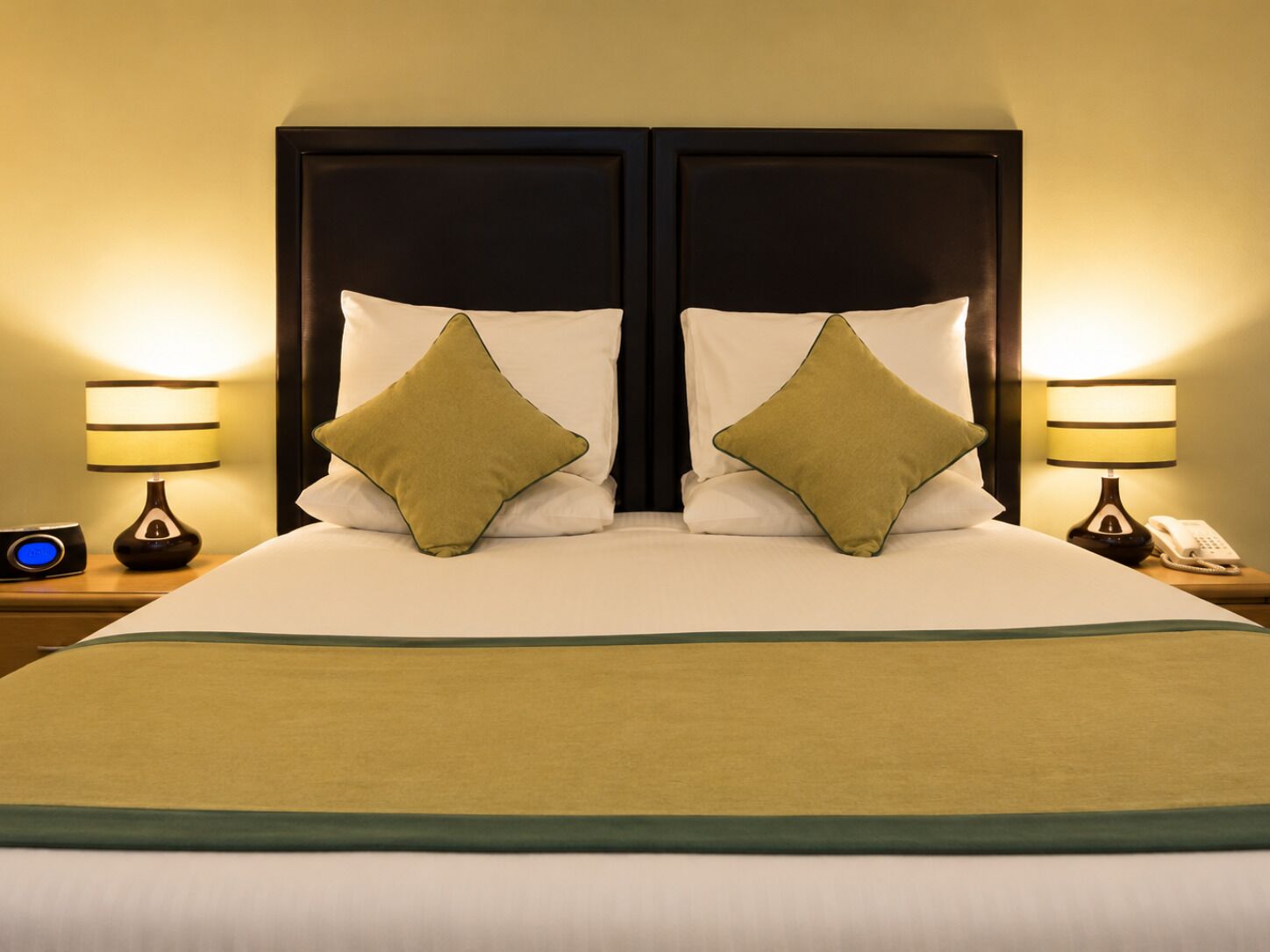 A double bed with two pillows, a bedside table with a lamp, and a phone.