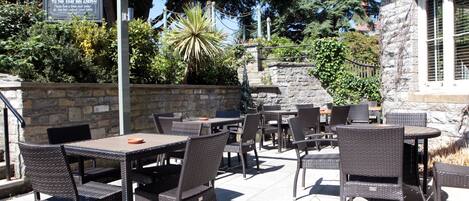 An outdoor patio area with wicker furniture and a stone wall.