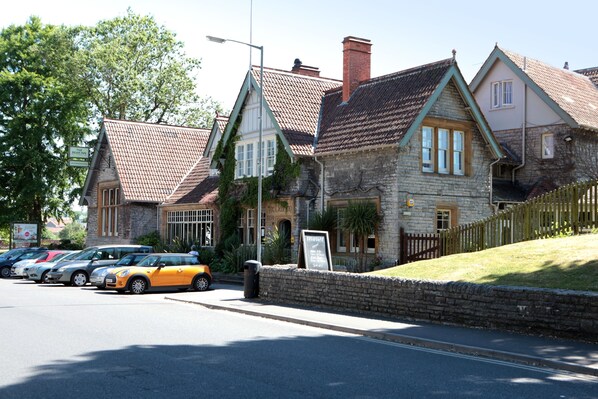 A row of parked cars in front of a stone building with a tiled roof.