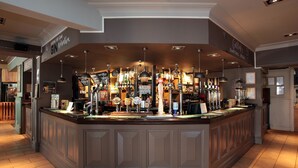 A bar area with a counter, various bottles, and a sign that reads "Gin Spritzers". - Bear Inn, Somerset by Marston's Inns (Street)