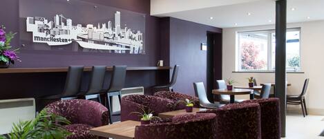 A modern hotel lobby with a cityscape mural, plush seating, and a large window offering a view.