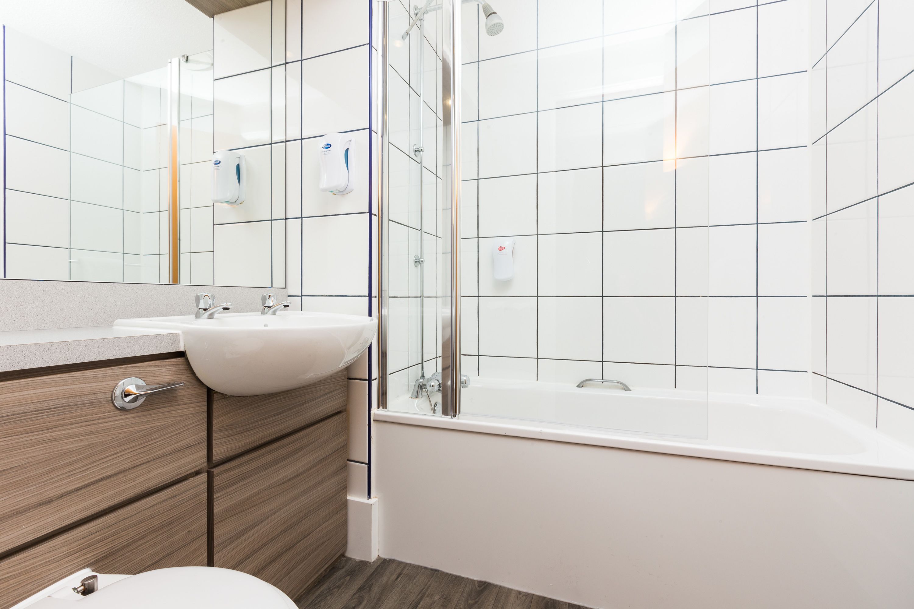 A modern bathroom with a glass-enclosed shower, a white sink, and a wooden vanity.