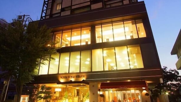 Un hotel moderno con una entrada destacada, amplias ventanas y fachada bien iluminada.