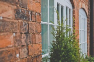 A brick building with a window and a plant in front.