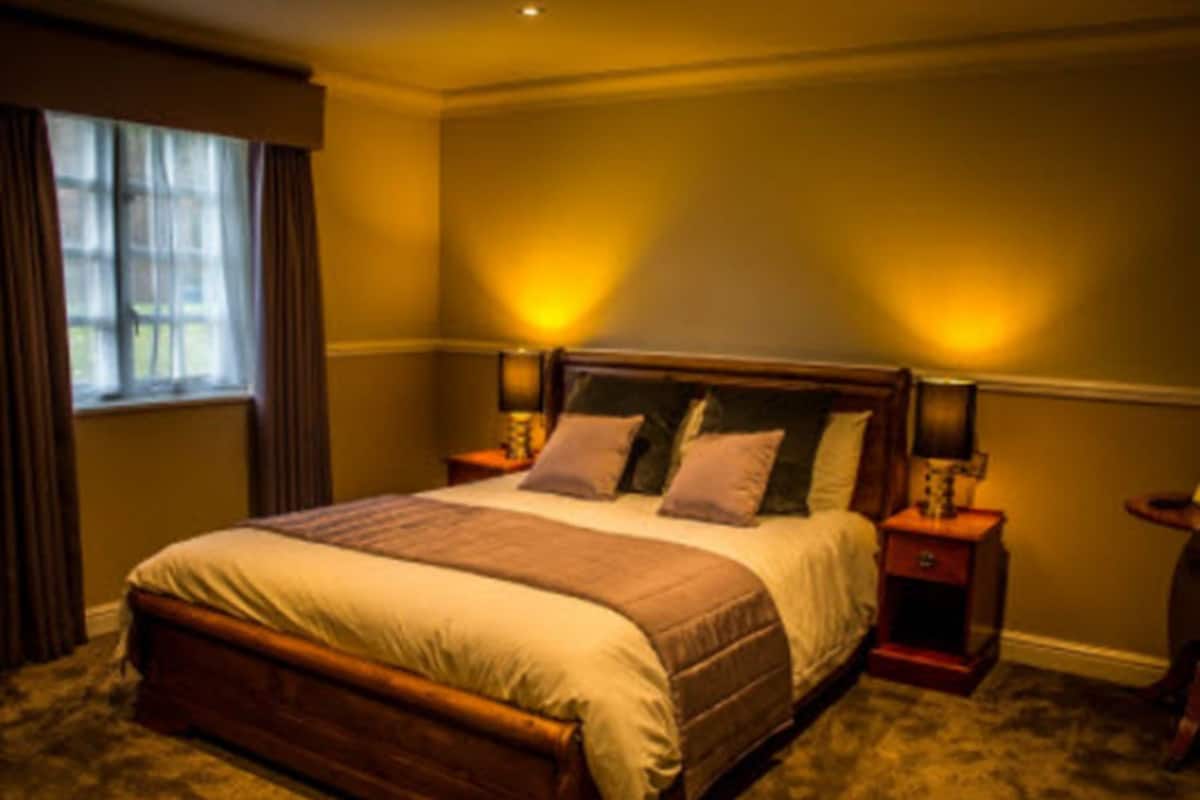 Quarto com uma cama grande, duas mesas de cabeceira e uma janela com cortinas.