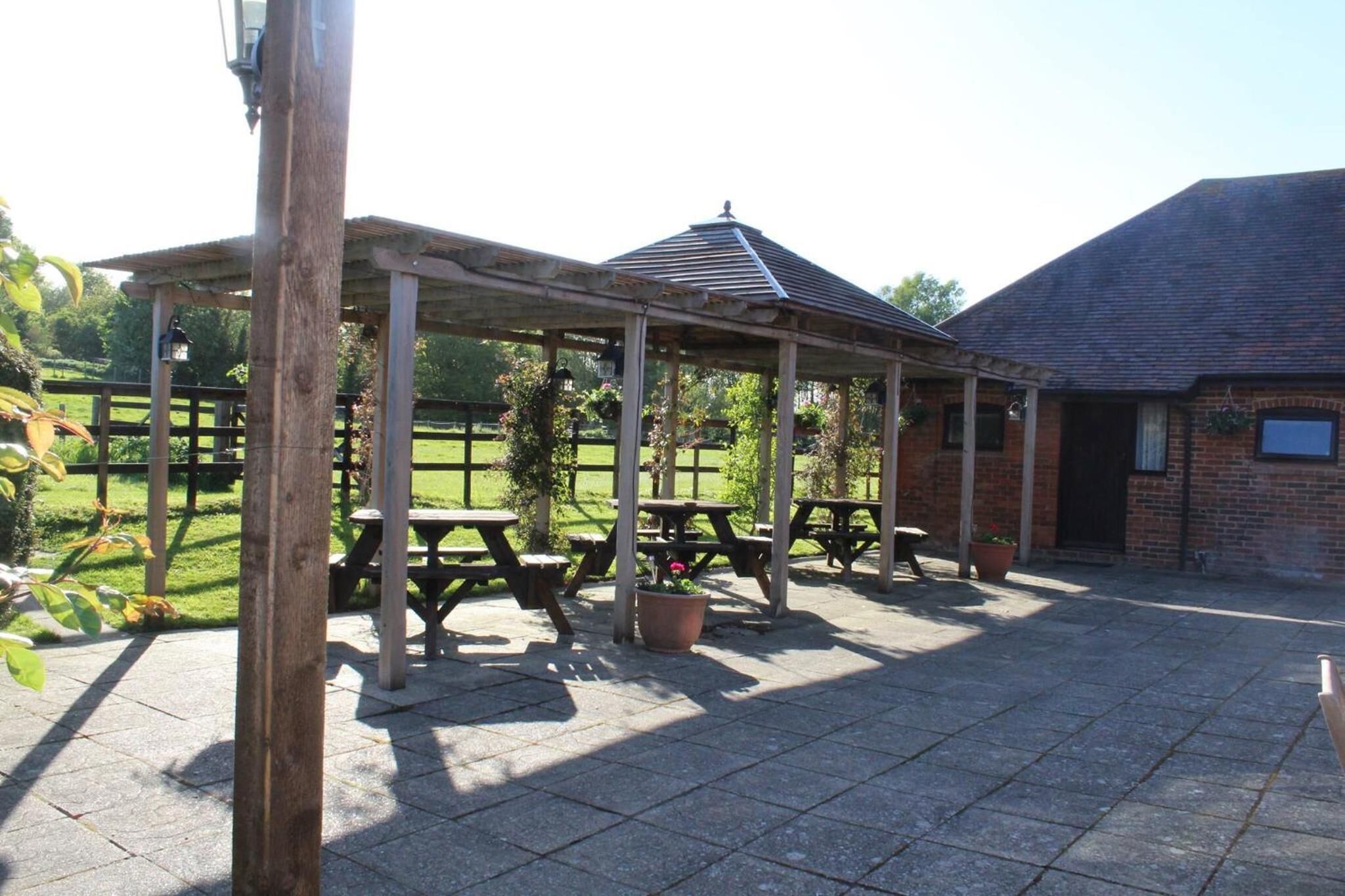 A covered outdoor seating area with picnic tables and potted plants.