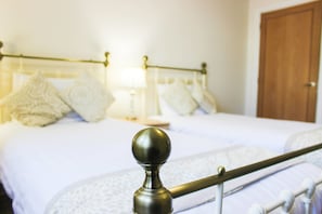 Quarto com cama, almofadas, mesa de cabeceira e porta.