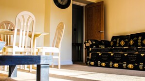 Un salon comprenant une table à manger, des chaises, un canapé et une horloge au mur.