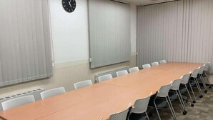 A conference room with a long table and chairs, a clock on the wall, and blinds on the windows. - Toyoko Inn Aomori-eki Shomen-guchi (AOMORI)