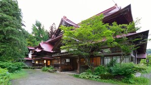 Un edificio japonés tradicional con camino de grava y abundante vegetación.
