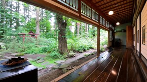 Un pasillo con suelo de madera y ventanas amplias que dan a un bosque.