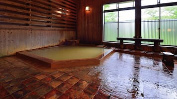 Un interior de madera con un espacio amplio, bancos y una ventana con vistas a zonas verdes.