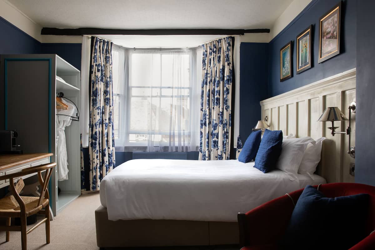 A hotel room with a bed, a desk, a chair, and a wardrobe.