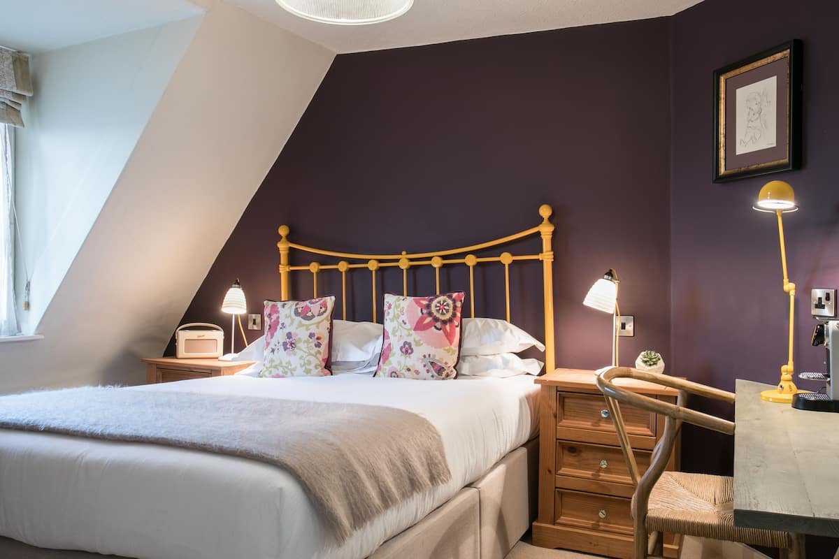 A bedroom with a bed, bedside lamps, a dresser, and a chair.