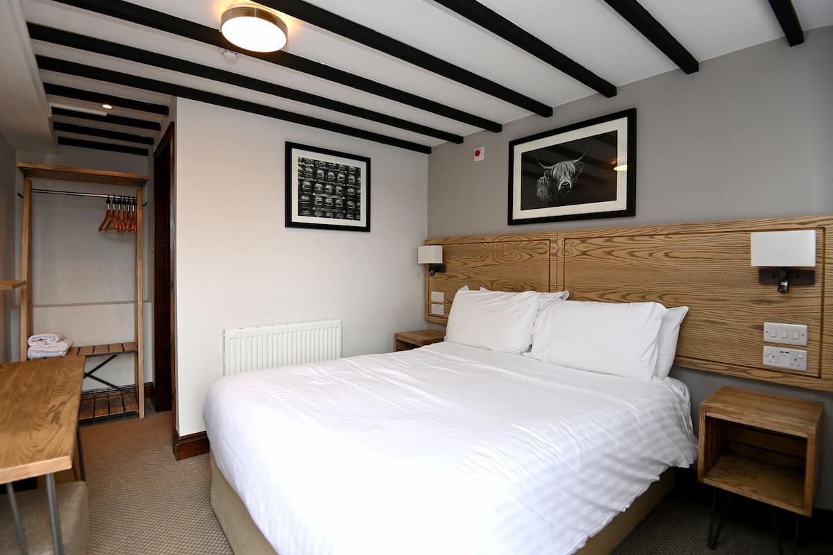 A neatly arranged bedroom with a large bed, wooden headboard, bedside tables, and a wardrobe.