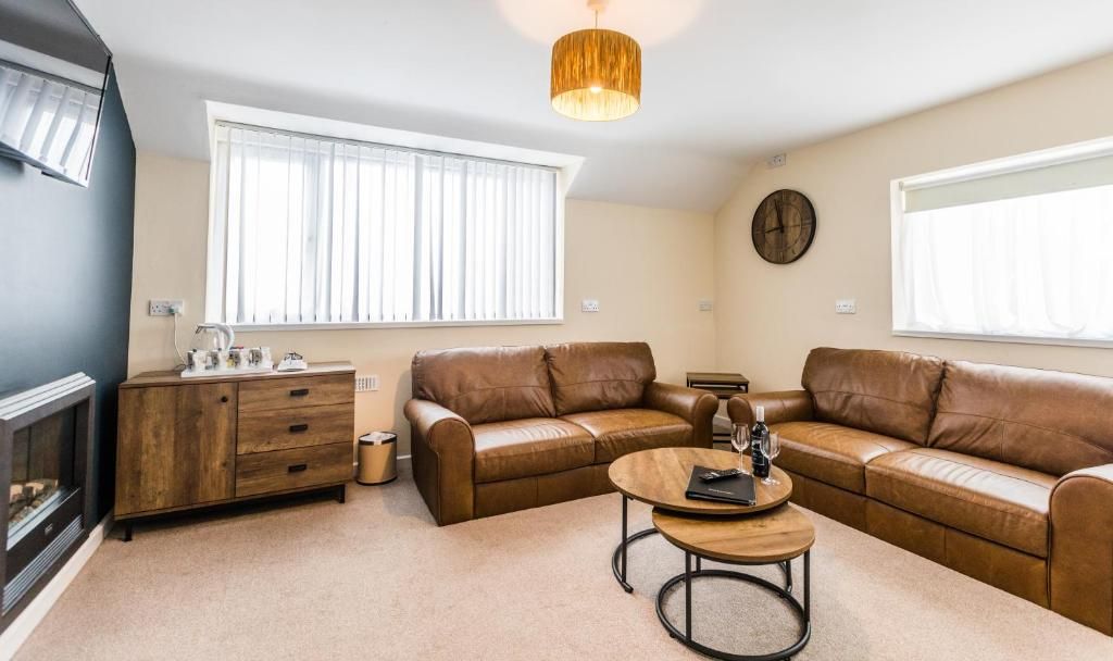 A living room with a fireplace, leather sofas, a coffee table, and a wooden cabinet.