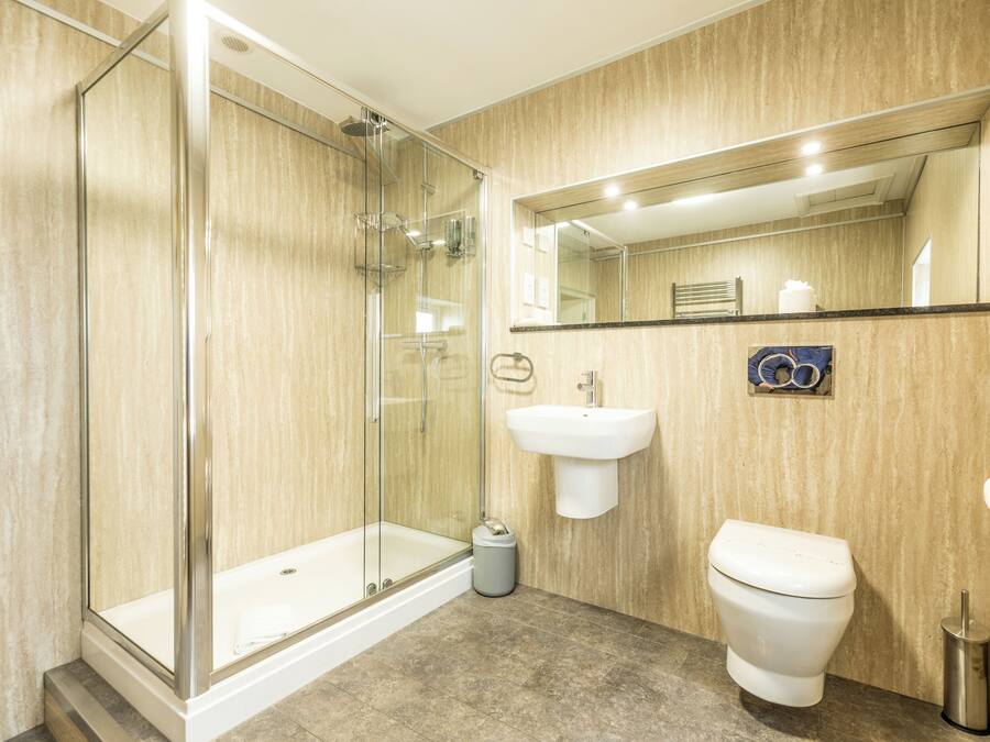 A modern bathroom with a glass-enclosed shower, a white sink, and a toilet.