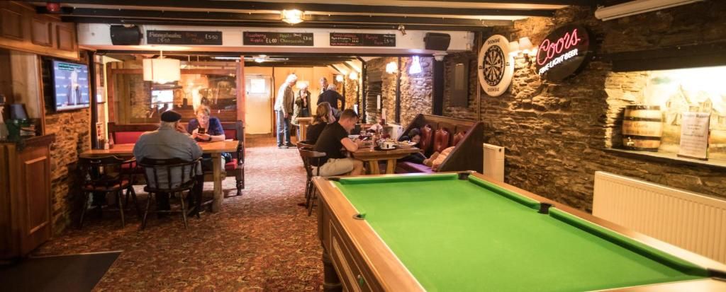 A billiards table in a room with stone walls and wooden furniture.