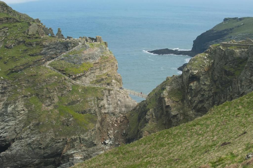 A coastal cliff with a narrow path leading to a small structure.