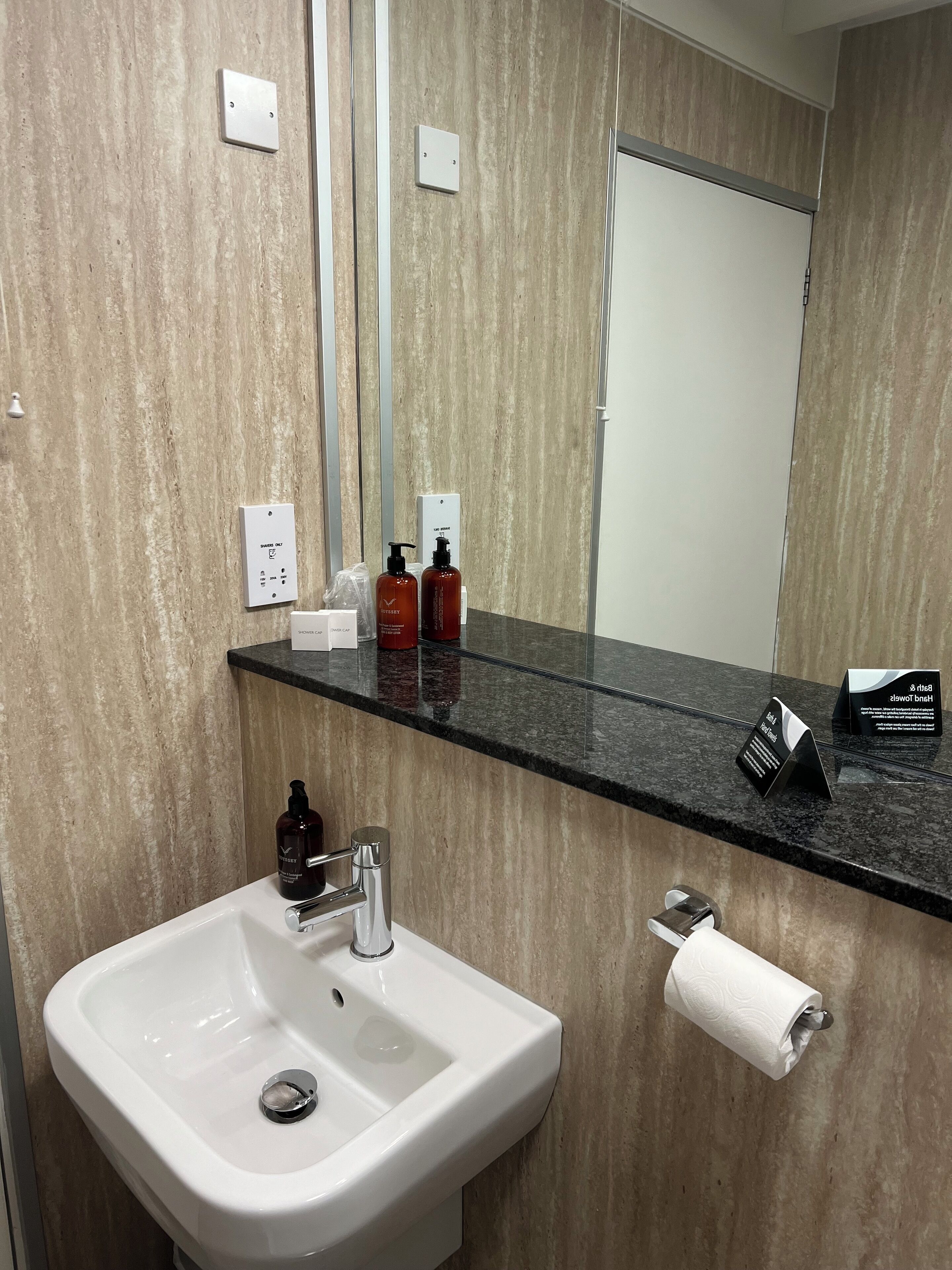 A modern bathroom with a white sink, a mirror, and a black countertop.