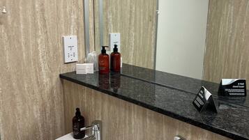 A modern bathroom with a white sink, a mirror, and a black countertop.