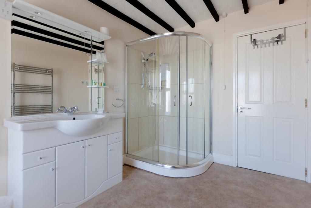 A bathroom with a glass-enclosed shower, a white sink, and a mirror above it.