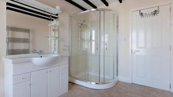 A bathroom with a glass-enclosed shower, a white sink, and a mirror above it.