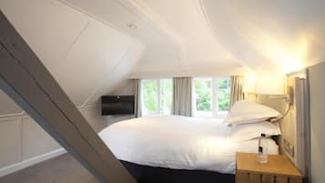 Habitación de hotel con una cama grande, un televisor en la pared y una ventana con cortinas.