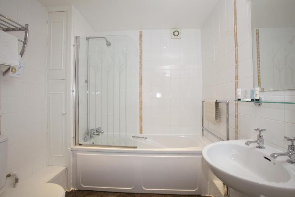 Un bagno con doccia vetrata, una vasca da bagno bianca e un lavabo con specchio.