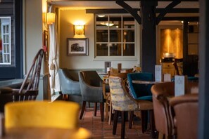 A cozy restaurant interior with wooden tables and chairs, a brick floor, and warm lighting. - Fisherman's Cot, Tiverton by Marston's Inns (Tiverton)