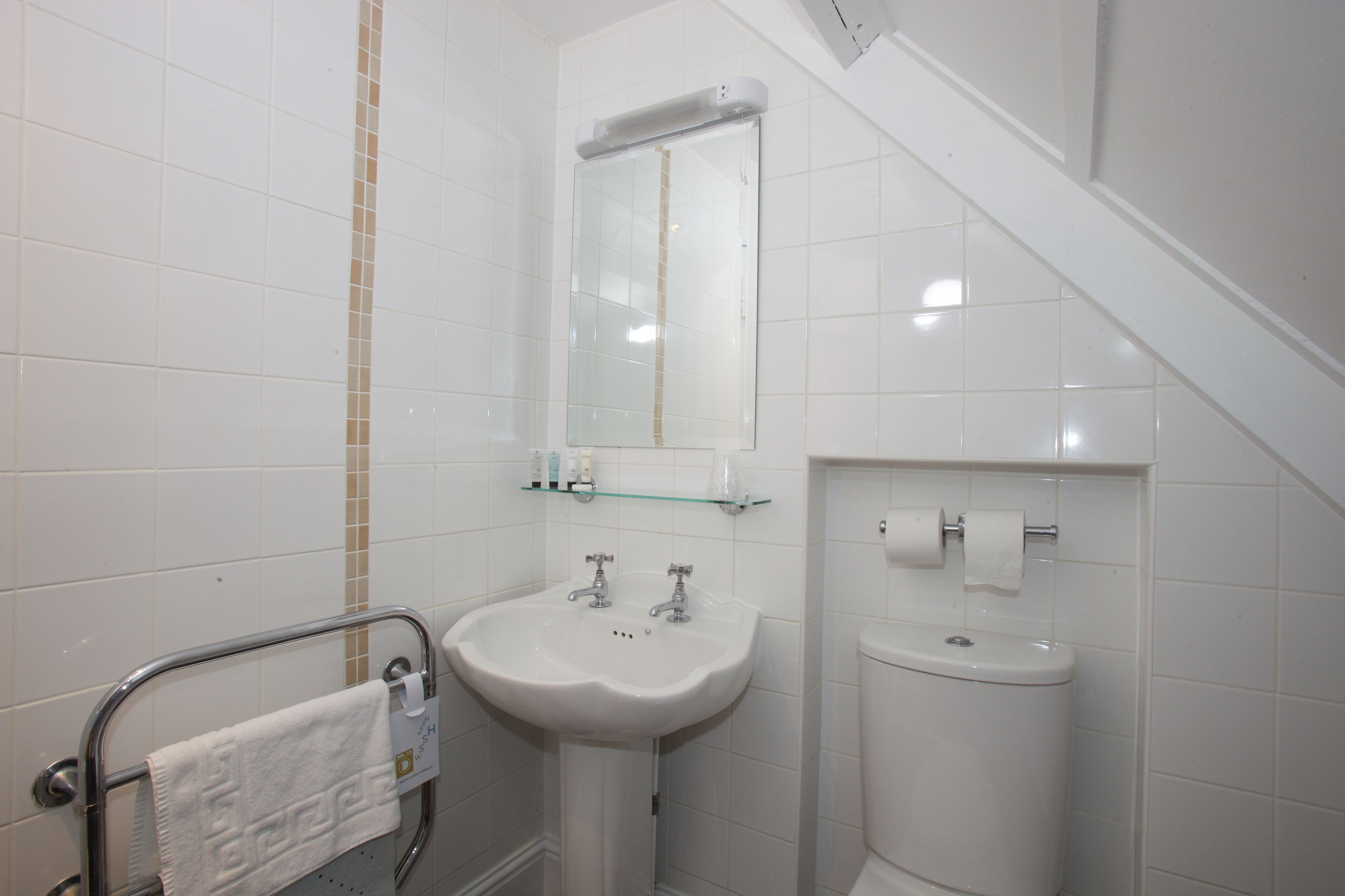 Une salle de bain avec un lavabo blanc, un miroir et des toilettes.
