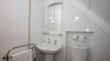 Une salle de bain avec un lavabo blanc, un miroir et des toilettes.