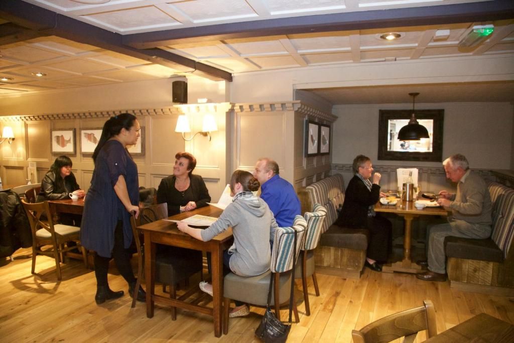 Un ambiente interior acogedor con mobiliario de madera, mesas y sillas dispuestas para comer y conversar.