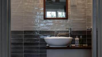 A bathroom with a vessel sink, a mirror, and a towel rack.