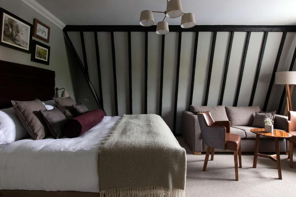 A hotel room with a bed, a sofa, a small table, and a lamp.