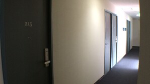 A hallway with doors numbered 215 and 216, carpeted floor, and a ceiling light. - @ Business Hotel Ichinoseki (Ichinoseki)