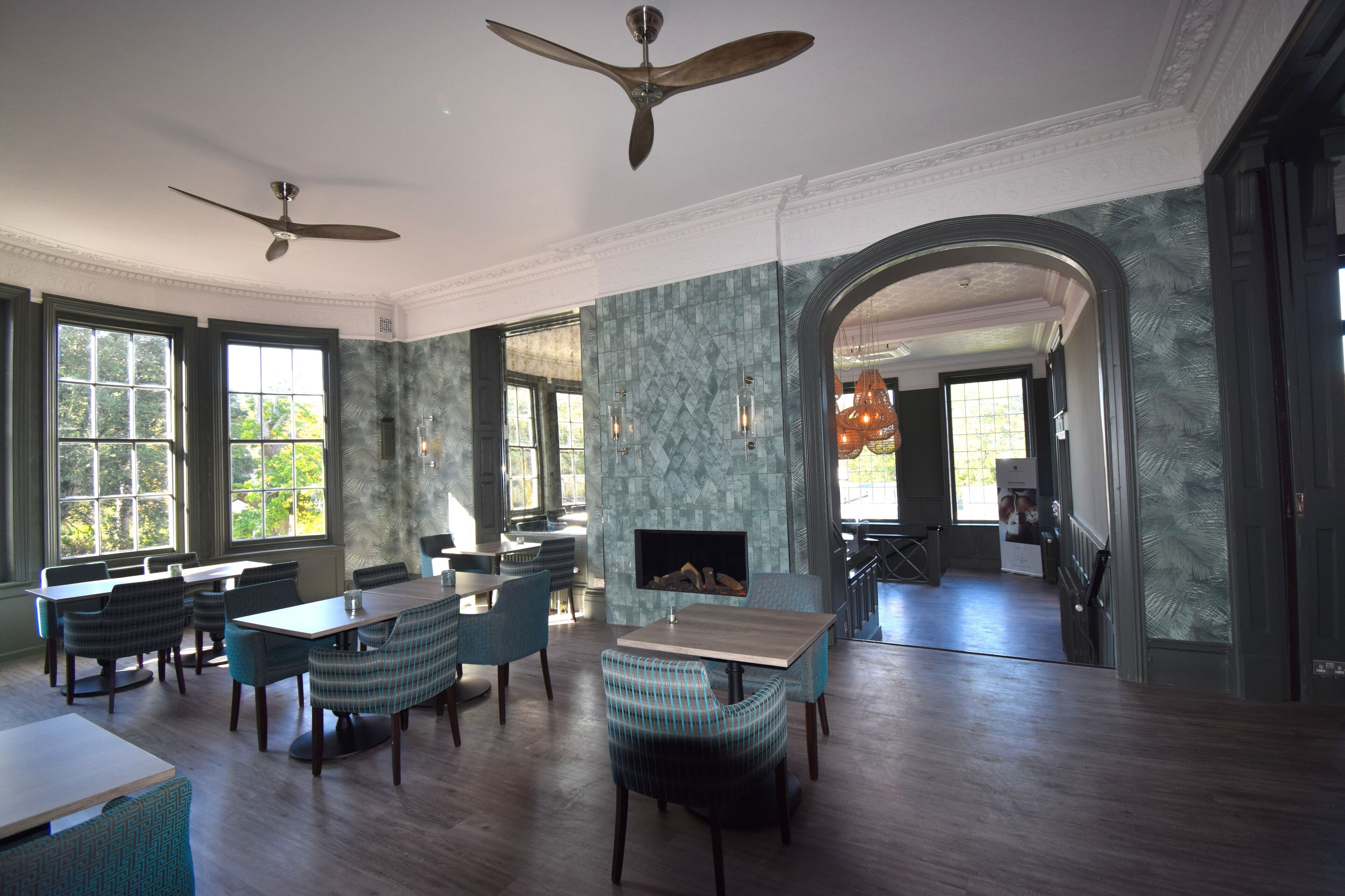 A spacious dining area with high ceilings, large windows, and a fireplace.