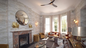 A spacious living room with a fireplace, leather sofas, a coffee table, and a large mirror. - Lincombe Hall Hotel & Spa - Just for Adults (Torquay)