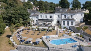 A large white building with a swimming pool, sun loungers, and umbrellas. - Lincombe Hall Hotel & Spa - Just for Adults (Torquay)
